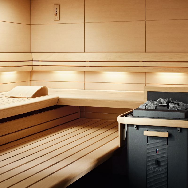 Holzbänke ruhen in einer gut beleuchteten Sauna mit modernem Ofen.