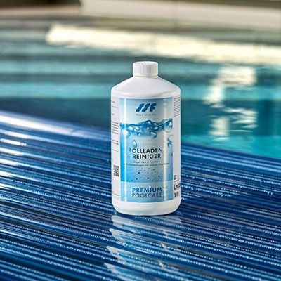 Flasche steht auf blauen Poolabdeckung, umgeben von reflektierendem Wasser. Text: „Rolladen Reiniger“.