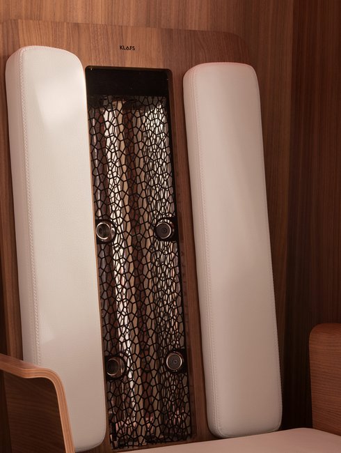 Weiße Polsterung sitzt auf Holzwand, elegant, in luxuriösem Saunaraum mit Netzstruktur und Beschriftung "KLAFS".