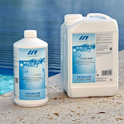 Zwei Flaschen, stehend, auf Steinboden am Pool, mit "Wintercare Premium Poolcare"-Etikett.